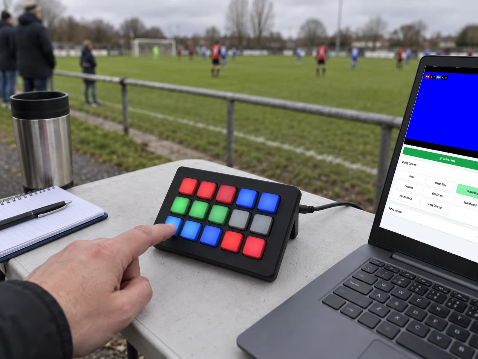 A fifteen-key control pad with coloured keys next to a laptop running PlayOverlay on a pitchside table
